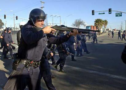 An Oakland Police officer fires a shotgun loaded with pellet-filled bean bags toward a group of anti-war protesters near the Port of Oakland, April 7, 2003. Oakland police fired rubber bullets and wooden pellets to disperse hundreds of anti-war protesters in what was believed to be the first such use against U.S. protesters since the American-led war on Iraq. (Tim Wimborne/Reuters)